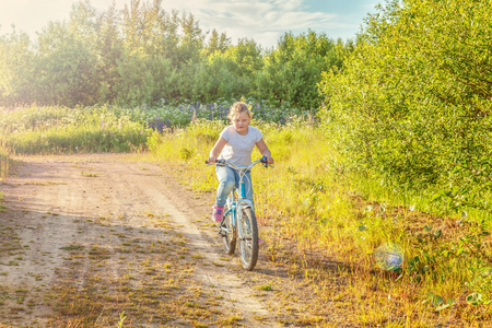 Happy child riding bike. Young girl on bicycle in sunny summer park. Healthy school children summer activity. Kids playing and cycling outdoors. Little girl learns to keep balance while riding bicycleの写真素材
