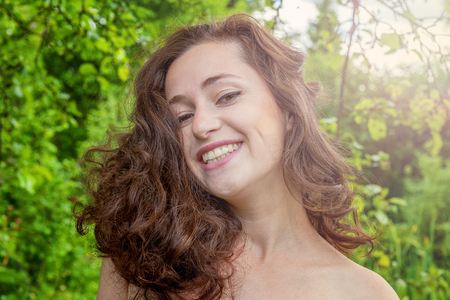 Beautiful young girl smiling on park background. European woman. Winning success positive human emotion, facial expression, body language, happy ecstatic celebrating being a winnerの写真素材
