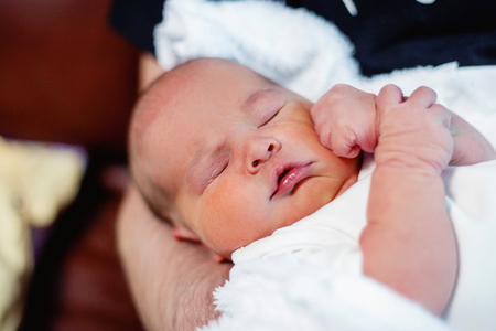 Soft portrait of peaceful sweet newborn infant baby lying on bed while sleeping in a bright room. Maternity family childhood innocence care conceptの写真素材