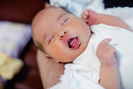 Soft portrait of peaceful sweet newborn infant baby lying on bed while sleeping in a bright room. Maternity family childhood innocence care conceptの写真素材