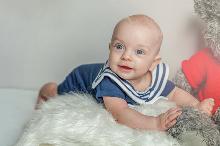 Infant toddler child baby boy lies on pillow with teddy bear toy relax and playing on white bedroom background. Family, maternity, tenderness, parenthood, responsibility, newborn, childhood conceptの写真素材