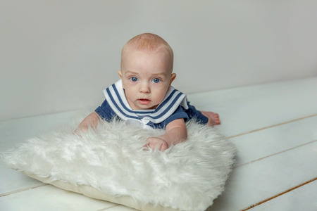 Infant toddler child baby boy lies on pillow relax and playing on white bedroom background. Family, maternity, tenderness, parenthood, responsibility, newborn, childhood conceptの写真素材
