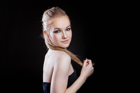 Beauty fashion model girl with long healthy smooth straight hair ponytail hairstyle on black background. Smiling pretty woman looking camera. Perfect Fresh Skin Portrait. Youth and Skin Care Conceptの写真素材