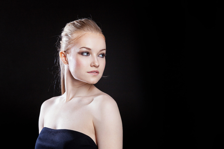 Beauty fashion model girl with long healthy smooth straight hair ponytail hairstyle on black background. Smiling pretty woman looking camera. Perfect Fresh Skin Portrait. Youth and Skin Care Conceptの写真素材
