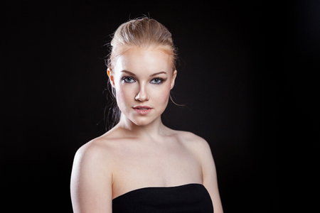 Beauty fashion model girl with long healthy smooth straight hair ponytail hairstyle on black background. Smiling pretty woman looking camera. Perfect Fresh Skin Portrait. Youth and Skin Care Conceptの写真素材