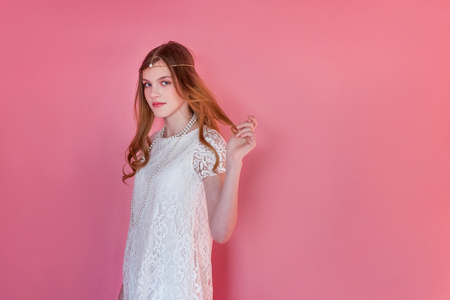 Happy teenage girl smiling. Closeup portrait young happy positive woman wearing white dress standing on pink colourful pastel trendy modern fashion pin-up background. European woman. Positive human emotion facial expression body languageの写真素材