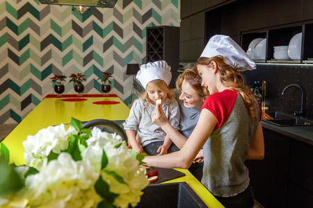 Happy family in kitchen. Mother and two children preparing dough, bake apple pie. Mom and daughters cooking healthy food at home and having fun. Household, teamwork helping, maternity conceptの写真素材