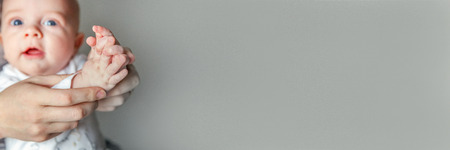 Young mother and newborn child clap their hands. Woman and infant new born boy relax and playing on white background. Family, maternity, tenderness, parenthood, responsibility concept. Bannerの写真素材