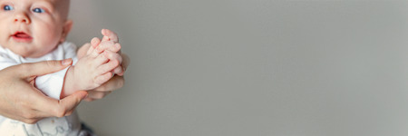 Young mother and newborn child clap their hands. Woman and infant new born boy relax and playing on white background. Family, maternity, tenderness, parenthood, responsibility concept. Bannerの写真素材