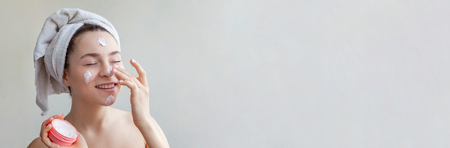 Beauty portrait of woman in towel on head with white nourishing mask or creme on face, white background isolated. Skincare cleansing eco organic cosmetic spa relax concept Bannerの写真素材
