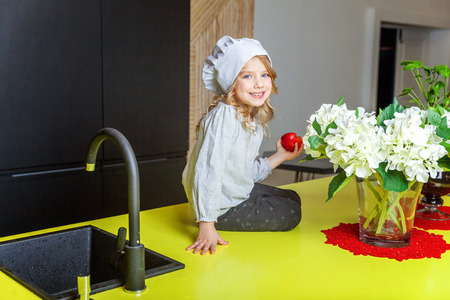 Little girl with chef hat learning cooking smiling in kitchen. Kid preparing healthy food at home and having fun. Childhood, food, healthy eating, household, teamwork, helping, family conceptの写真素材