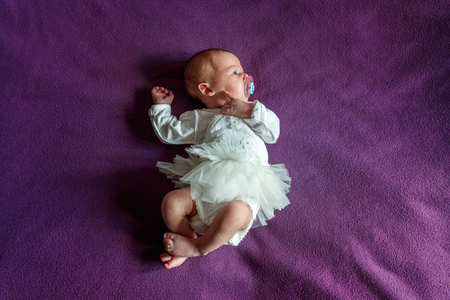 Soft portrait of peaceful sweet newborn infant baby lying on bed while sleeping in purple blanket background. Sweet dream, good night. Maternity family childhood innocence care conceptの写真素材