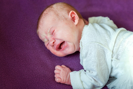 Soft portrait of peaceful sweet newborn infant baby lying on bed while sleeping in purple blanket background. Sweet dream, good night. Maternity family childhood innocence care conceptの写真素材