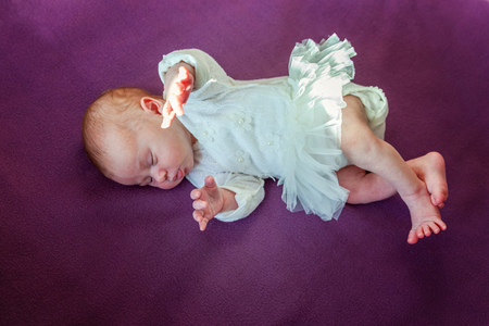 Soft portrait of peaceful sweet newborn infant baby lying on bed while sleeping in purple blanket background. Sweet dream, good night. Maternity family childhood innocence care conceptの写真素材