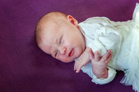 Soft portrait of peaceful sweet newborn infant baby lying on bed while sleeping in purple blanket background. Sweet dream, good night. Maternity family childhood innocence care conceptの写真素材