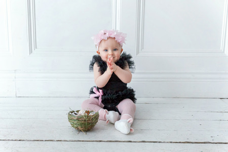 Little child girl wearing spring wreath on Easter day. Girl holding basket with painted eggs at home decoration, having fun on Easter egg hunt. Happy Easter holiday celebration conceptの写真素材
