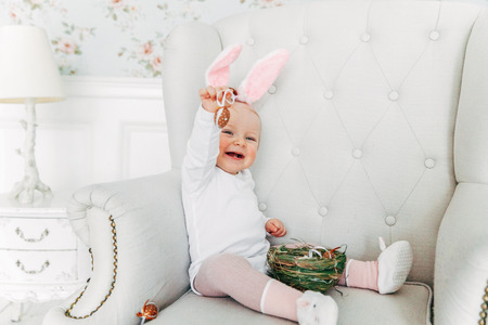Little child girl wearing bunny ears on Easter day. Girl holding basket with painted eggs at home decoration, having fun on Easter egg hunt. Happy Easter holiday celebration spring conceptの写真素材