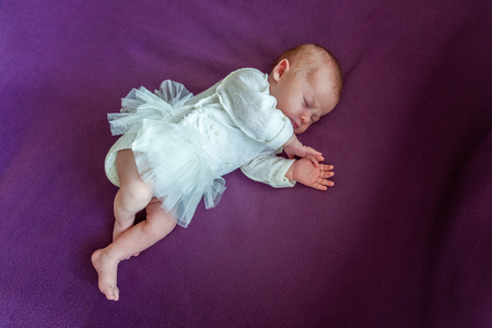 Soft portrait of peaceful sweet newborn infant baby lying on bed while sleeping in purple blanket background. Sweet dream, good night. Maternity family childhood innocence care conceptの写真素材