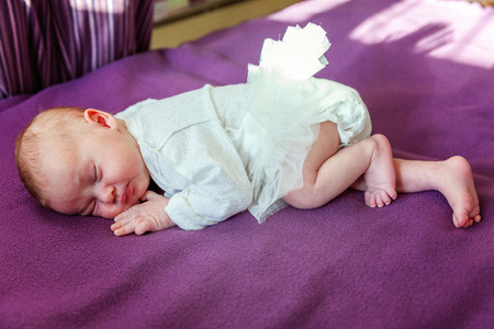 Soft portrait of peaceful sweet newborn infant baby lying on bed while sleeping in purple blanket background. Sweet dream, good night. Maternity family childhood innocence care conceptの写真素材