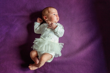 Soft portrait of peaceful sweet newborn infant baby lying on bed while sleeping in purple blanket background. Sweet dream, good night. Maternity family childhood innocence care conceptの写真素材
