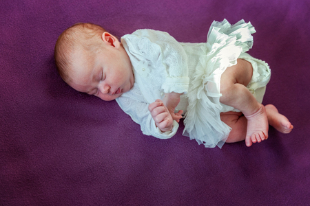 Soft portrait of peaceful sweet newborn infant baby lying on bed while sleeping in purple blanket background. Sweet dream, good night. Maternity family childhood innocence care conceptの写真素材