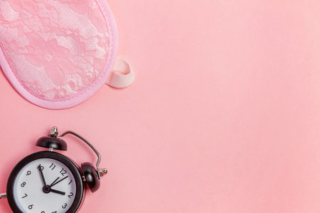 Sleeping eye mask, alarm clock isolated on pink pastel colourful trendy background. Do not disturb me, let me sleep. Rest, good night, siesta, insomnia, relaxation, tired, travel conceptの写真素材