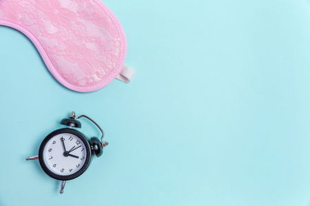 Sleeping eye mask, alarm clock isolated on blue pastel colourful trendy background. Do not disturb me, let me sleep. Rest, good night, siesta, insomnia, relaxation, tired, travel conceptの写真素材