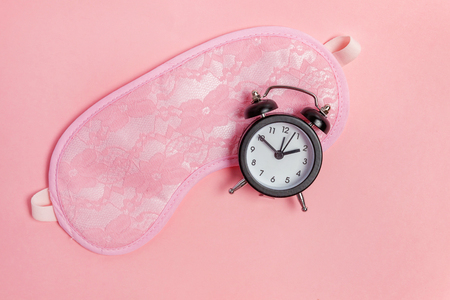 Sleeping eye mask, alarm clock isolated on pink pastel colourful trendy background. Do not disturb me, let me sleep. Rest, good night, siesta, insomnia, relaxation, tired, travel conceptの写真素材