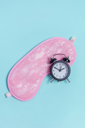 Sleeping eye mask, alarm clock isolated on blue pastel colourful trendy background. Do not disturb me, let me sleep. Rest, good night, siesta, insomnia, relaxation, tired, travel conceptの写真素材