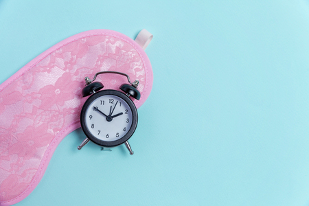 Sleeping eye mask, alarm clock isolated on blue pastel colourful trendy background. Do not disturb me, let me sleep. Rest, good night, siesta, insomnia, relaxation, tired, travel conceptの写真素材