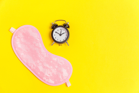 Sleeping eye mask, alarm clock isolated on yellow colourful trendy background. Do not disturb me, let me sleep. Rest, good night, siesta, insomnia, relaxation, tired, travel conceptの写真素材