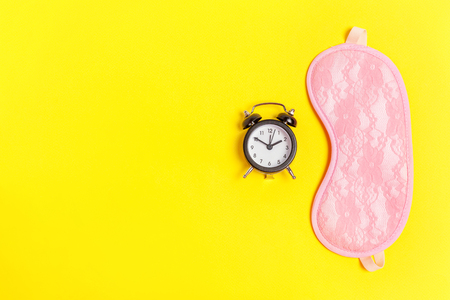 Sleeping eye mask, alarm clock isolated on yellow colourful trendy background. Do not disturb me, let me sleep. Rest, good night, siesta, insomnia, relaxation, tired, travel conceptの写真素材
