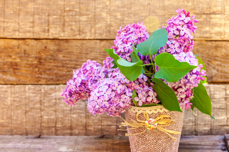 Ecology nature springtime concept. Bouquet of flowers beautiful smell violet purple lilac in vase on rustic wooden background. Inspirational natural floral spring blooming garden or parkの写真素材