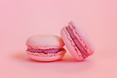 Sweet almond colorful unicorn pink macaron or macaroon dessert cake isolated on trendy pink pastel background. French sweet cookie. Minimal food bakery concept. Copy spaceの写真素材