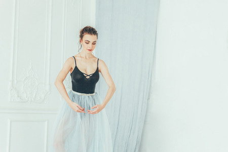 Young classical ballet dancer woman in dance class. Beautiful graceful ballerina practice ballet positions in blue tutu skirt near large mirror in white light hallの写真素材