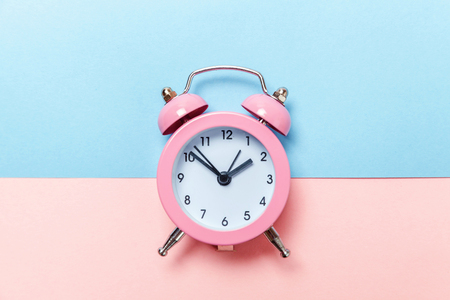 Ringing twin bell vintage classic alarm clock Isolated on blue pink pastel colorful trendy background. Rest hours time of life good morning night wake up awake concept. Flat lay top view copy spaceの写真素材