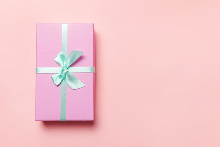 Christmas New Year birthday valentine celebration present romantic concept. Small gift box wrapped pink paper isolated on pink pastel colorful trendy background. Flat lay top view copy spaceの写真素材