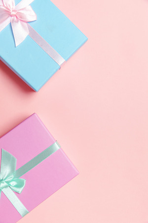Christmas New Year birthday valentine celebration present romantic concept. Small gift box wrapped pink and blue paper isolated on pink pastel colorful trendy background. Flat lay top view copy spaceの写真素材