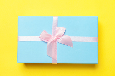 Christmas New Year birthday valentine celebration present romantic concept. Gift box wrapped blue paper isolated on yellow colourful trendy modern fashion background. Flat lay top view copy spaceの写真素材