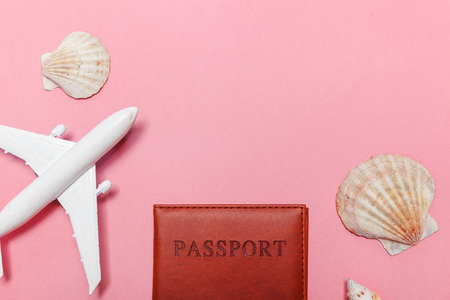 Travel by plane vacation summer weekend adventure trip journey ticket tour concept. Minimal simple flat lay with plane passport and shell on pink pastel trendy modern background. Tourist essentialsの写真素材