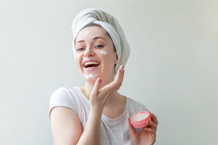 Beauty portrait of woman in towel on head with white nourishing mask or creme on face, white background isolated. Skincare cleansing eco organic cosmetic spa relax conceptの写真素材