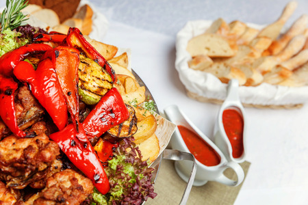 Mixed grill meat, fried vegetables and grilled salmon fish fillets decoration in warm dish. Assorted delicious grilled kebab served with herbs on platter. Restaurant menu plateの写真素材