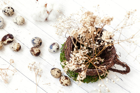 Easter decoration with egg in nest cup on white wooden background. Easter concept. Flat lay top view...