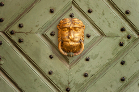Golden door knocker in the shape of lion with ring on a wooden doorのeditorial素材