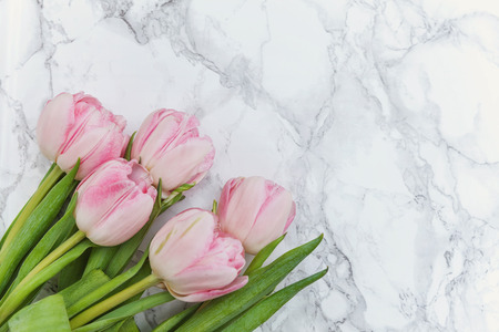 Spring greeting card. Bouquet of fresh light pastel pink tulips flowers on marble background. Happy holiday easter mother day anniversary valentine day birthday concept. Flat lay top view copy spaceの写真素材