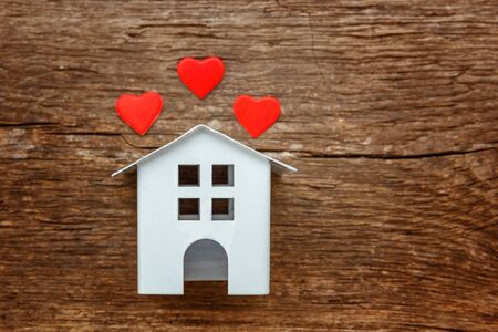 Miniature white toy house with red hearts on a rustic old vintage wooden background. Mortgage property insurance dream home conceptの写真素材