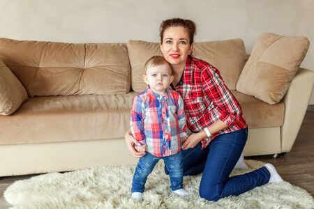 Young mother playing with her young daughter. Woman and new born girl relax in a bedroom. Mother...