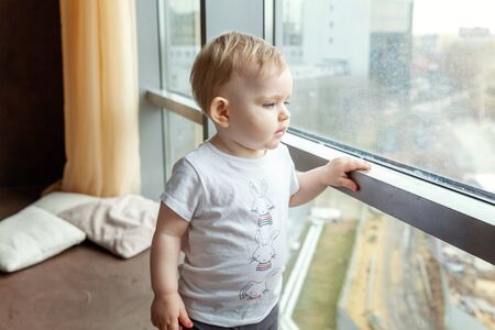 Cute smiling baby standing at home near windowの写真素材