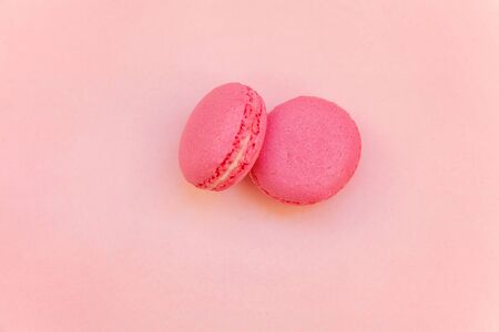 Top view of mini pink macaron or macaroon french desserts cake on soft sweet pink pastel paper flat lay backgroundの写真素材