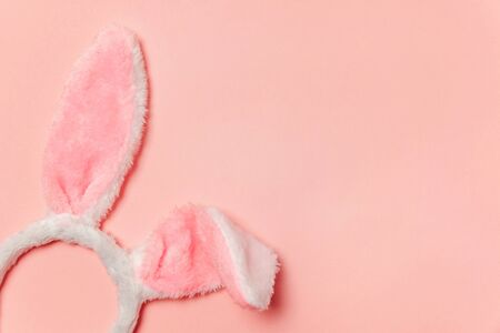 Happy Easter concept. Preparation for holiday. Decorative bunny ears furry fluffy costume toy isolated on trendy pastel pink background. Simple minimalism flat lay top view copy spaceの写真素材